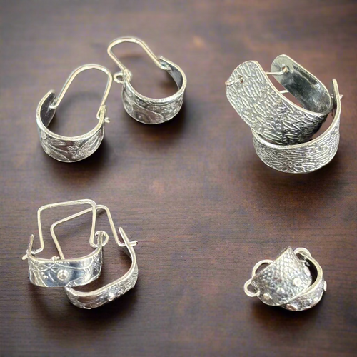Silver hoop earrings on a wooden surface. Silver Metal Clay Class with Carrie Story. 