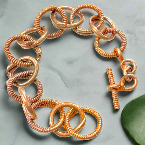 Rose gold bracelet with a clasp on a white background. Bronze Base Metal Clay Class with Carrie Story. 