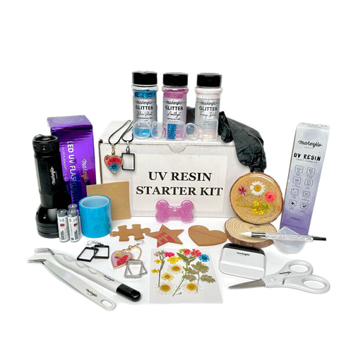 A UV Resin Starter Kit containing various crafting materials such as resin, glitters, silicone molds, a UV flashlight, and other crafting tools arranged on a table.